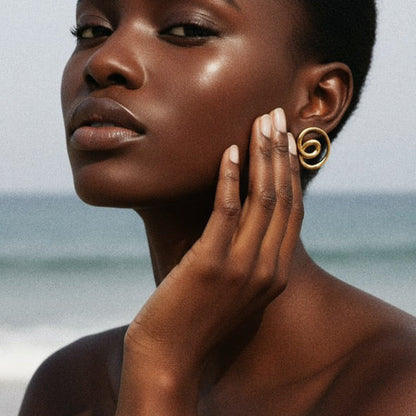 Woman wearing gold earrings and bracelet with a blurred ocean background