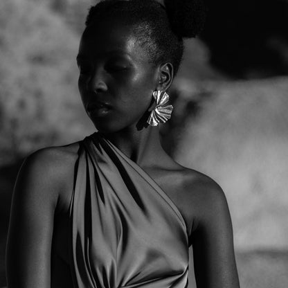 Woman wearing a one-shoulder dress with a blurred natural background