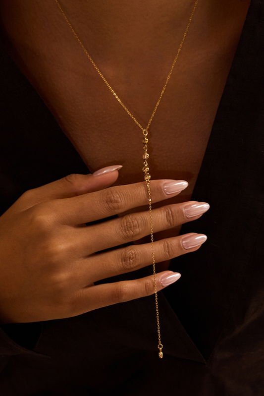 Gold body chain worn by a person with a dark background